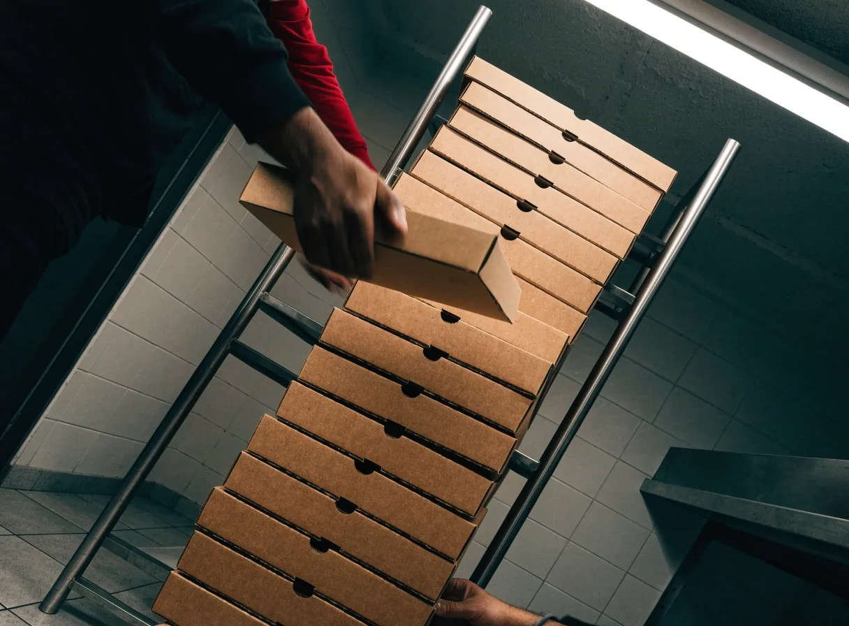 Stack of closed pizza boxes on a steel rack